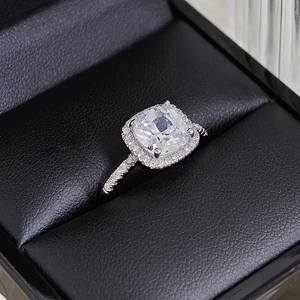 Macro shot of cushion cut halo diamond ring on black leather textured jewelry box