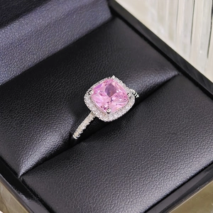 Macro shot of cushion-cut pink gemstone ring with halo diamonds on black leather box