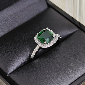 Macro shot of halo setting emerald green square ring on black leather jewelry box