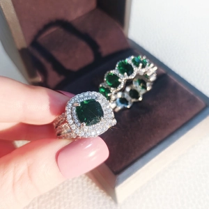 Macro shot of emerald halo ring with triple row diamonds and matching eternity band