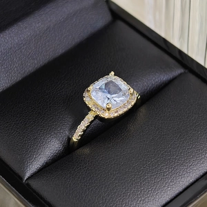 Close-up of luxury gold square halo ring with cushion cut stone on black leather box