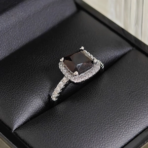 Macro shot of a luxury square-cut brown gemstone ring with halo diamond setting on a leather box