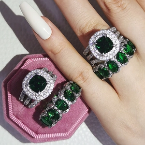 Close-up of four luxury emerald green zircon rings on a velvet box with sparkling diamonds