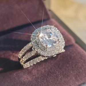 Macro shot of cushion cut crystal ring with halo pavé diamonds in purple velvet box