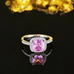 Luxury square pink cushion cut ring with halo setting on a black reflective surface