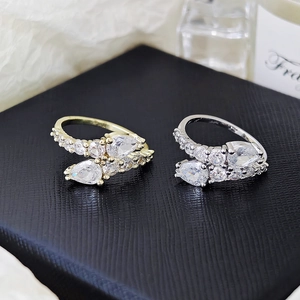 Detail view of gold and silver snake rings with pear-cut zircon on black velvet