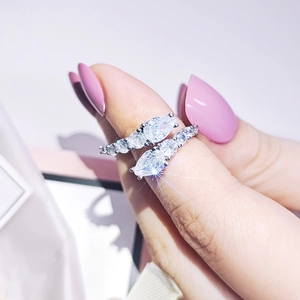 Close-up of silver dual-layer cross ring with pear-cut cubic zirconia on a female finger