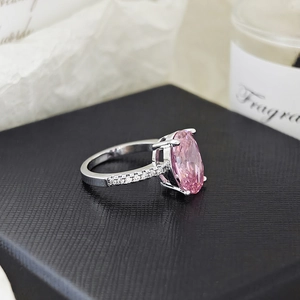 Vista macro de anillo plateado con gran circón rosa óvalo y diamantes sobre un estuche