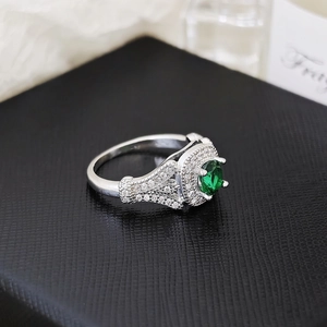 Macro de un anillo de plata con circón verde grande y doble halo de piedras blancas