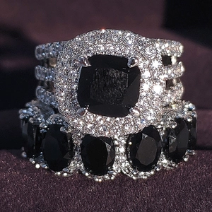 Macro shot of silver wedding ring set featuring large black square gemstone and halo crystals