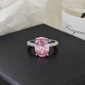 Vista macro de un anillo con gran piedra rosa ovalada y banda de plata con micro pavé