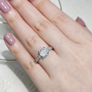Close-up of four-prong round zircon ring with side stones on model finger