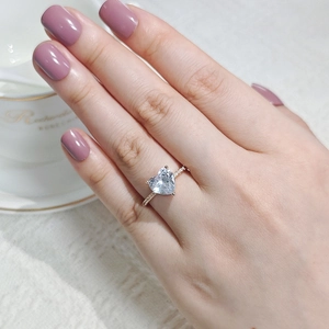 Nahaufnahme eines Zirkonrings mit Herzschliff und Pavé-Band, getragen von einem Modell