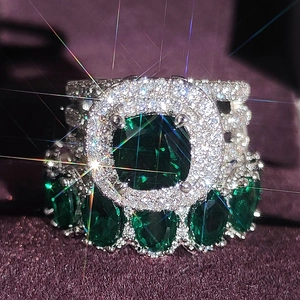 Luxury silver ring featuring a large green cushion-cut emerald with brilliant diamond halo