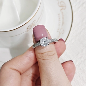 Detailed view of elegant silver ring with central zircon and pave diamond setting on finger