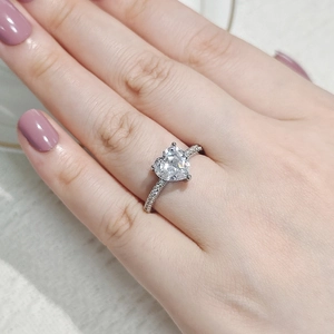 Nahaufnahme eines herzförmigen Zirkonrings mit Pavé-Besatz an der Hand eines Models