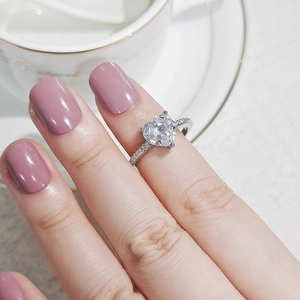 Detailaufnahme eines herzförmigen Zirkonrings mit Mikropflaster-Fassung an der Hand