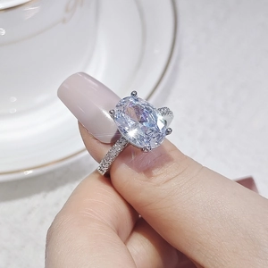Vista macro de una mano sosteniendo un anillo de circonita ovalada con engaste de plata