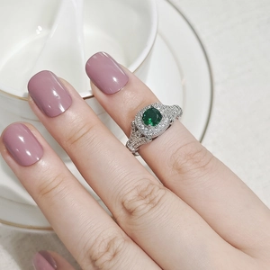 Primer plano de anillo vintage con halo de esmeralda verde y banda de circonitas
