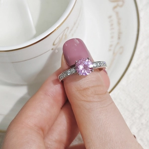 Close-up of a silver ring with a pink zircon stone and white accent crystals