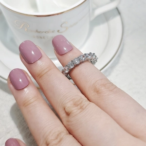 Close-up of silver eternity ring with zircon stones worn by a model with manicured nails