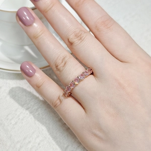 Detailed view of rose gold ring set with sparkling pink zircons on a model's hand