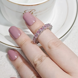 Detailed close-up of a silver band ring featuring sparkling round-cut pink zircon stones