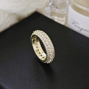 Macro shot of triple-row gold pavé zircon ring with sparkling clear stones detail