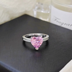 Macro shot of silver ring featuring heart-shaped pink gemstone and side accent stones