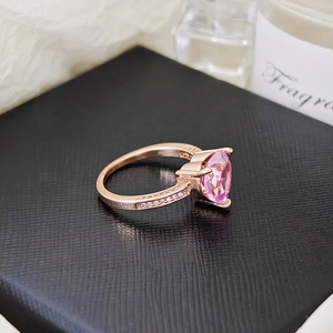 Detailed close-up of rose gold ring with heart-shaped pink stone on black gift box lid