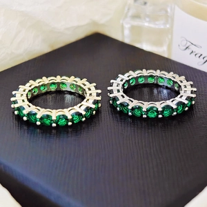 Gold and silver eternity rings with round cut green zircon stones on black leather pad