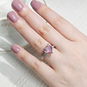 Detail of a pink heart-cut gemstone ring with silver band and micro-inlaid side diamonds
