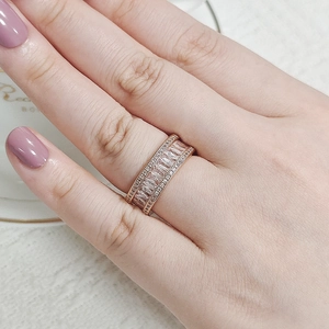 Detail of rose gold wide ring with baguette-cut and round crystals in a triple row