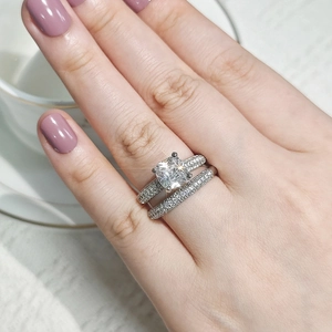 Close-up of stacked silver rings with a square pink diamond and micro-pave setting