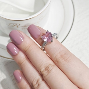 Close-up of heart-shaped pink gemstone ring with side-stone accents on a hand