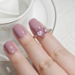 Close-up of rose gold ring with heart-shaped pink gemstone and side diamonds