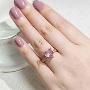 Close-up of a rose gold heart ring with pink zircon and micro-pave diamonds on the band