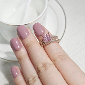 Close-up of rose gold wedding band set with pink square cut stone on finger
