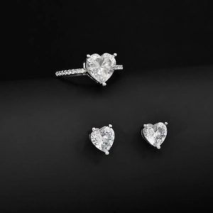 Detail eines herzförmigen Zirkonia-Schmucksets mit Ring und Ohrsteckern auf dunklem Grund