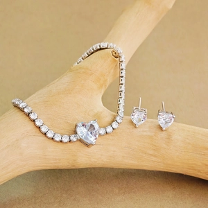 Detailansicht von Herz-Zirkonia-Armband und Ohrringen auf einem Naturholzständer