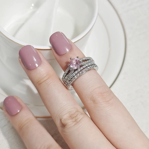 Close-up of elegant pink gemstone ring set with sparkling side bands on hand