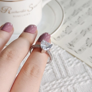 Close-up of heart-shaped zircon ring on hand with silver pave setting and elegant background