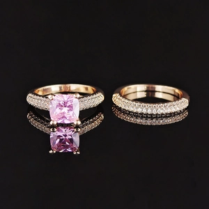 Pink cushion cut gemstone ring set with sparkling pave diamonds on golden bands