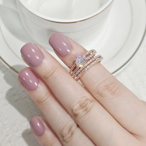 Detailed close-up of rose gold stacked rings with a round main stone and micro-pave diamonds