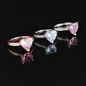 Three elegant heart-shaped zircon rings in rose gold and silver on a black mirror surface