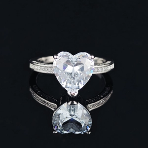 Classic silver heart-shaped cubic zirconia ring with pavé stones on a black background