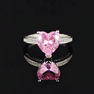 Elegant silver ring with pink heart shaped gemstone and pavé diamonds on a black mirror