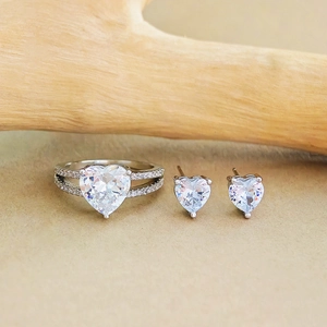 Elegantes Zirkonia-Schmuckset in Herzform mit Silberring und Ohrsteckern auf Holzdekor
