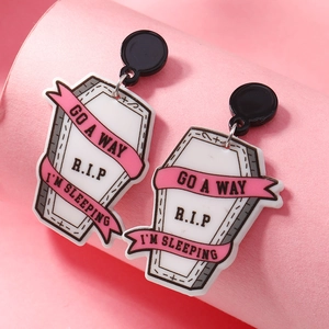 Gothic Halloween acrylic coffin earrings with RIP engraving on a pink background