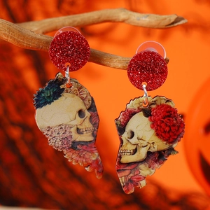 Halloween acrylic skull earrings with red floral patterns hanging on a wood branch
